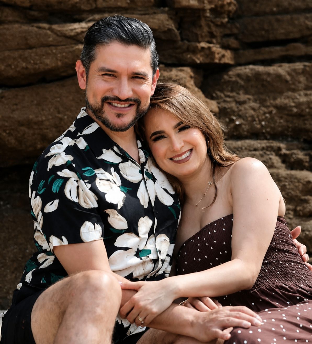 Michelle y Efrén Ruiz sentados juntos frente a una pared de roca, abrazados y sonriendo.