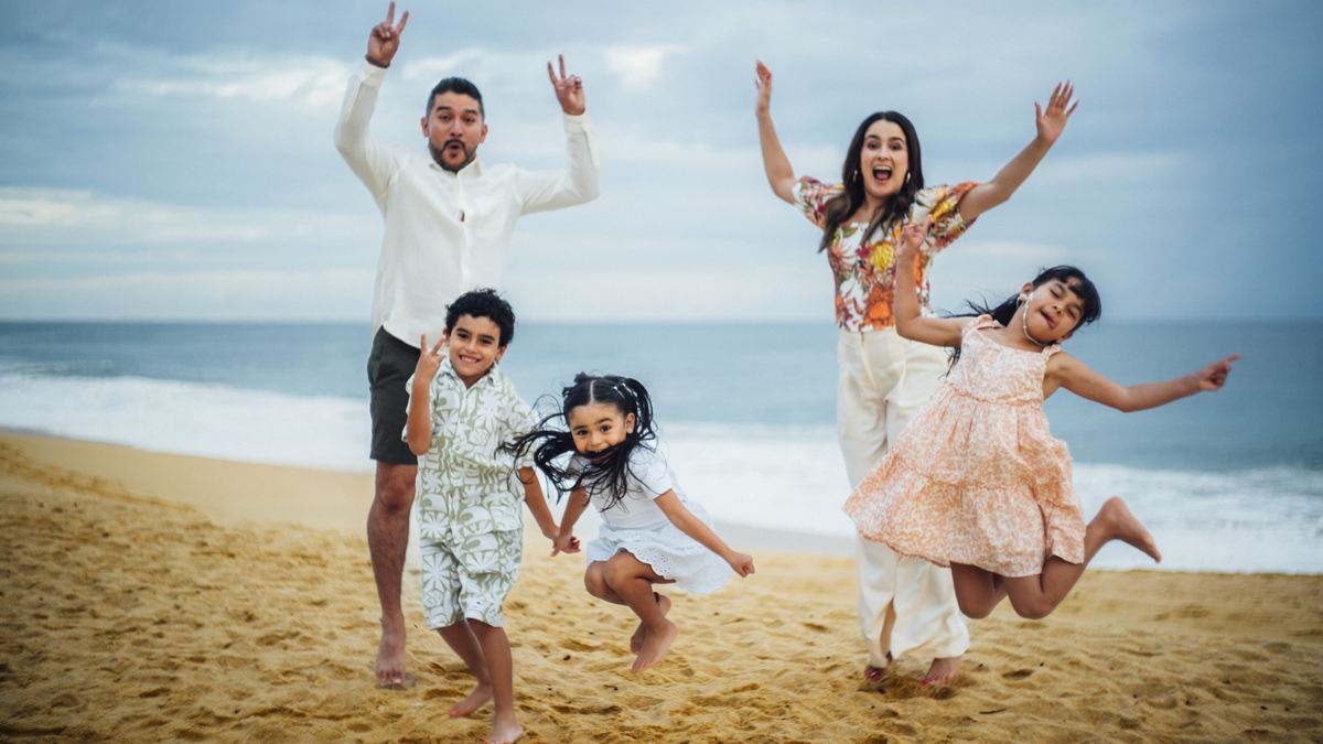 La familia Ruiz saltando y riendo en la playa: Michelle, Efrén y sus tres hijos.