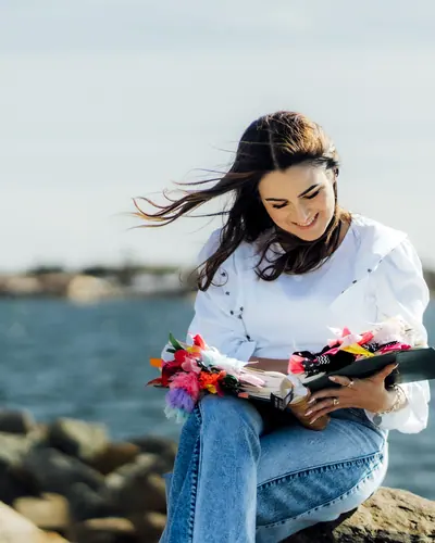 Michelle Ruiz sentada frente al agua con su Biblia abierta sobre las piernas.