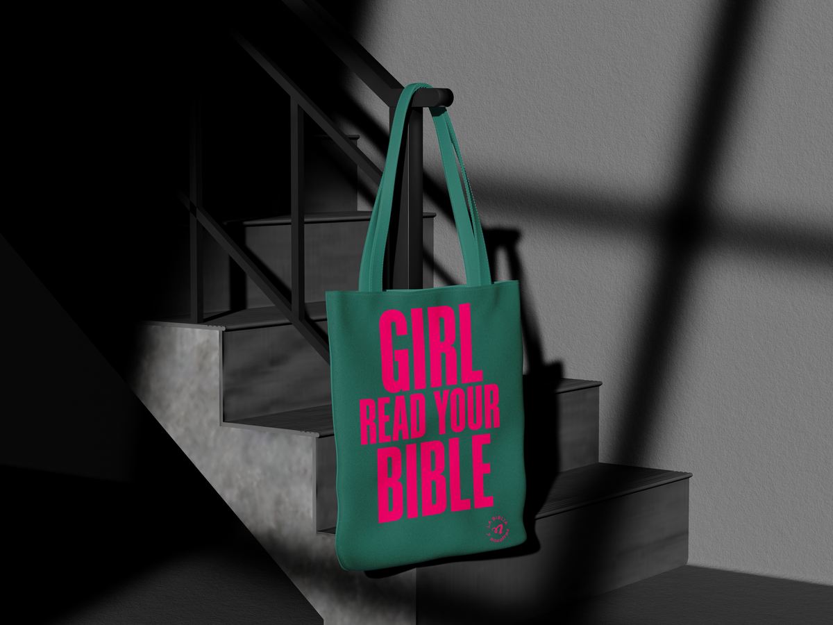 Bolsa de tela verde colgada, con la frase «Girl read your bible» en rosa.
